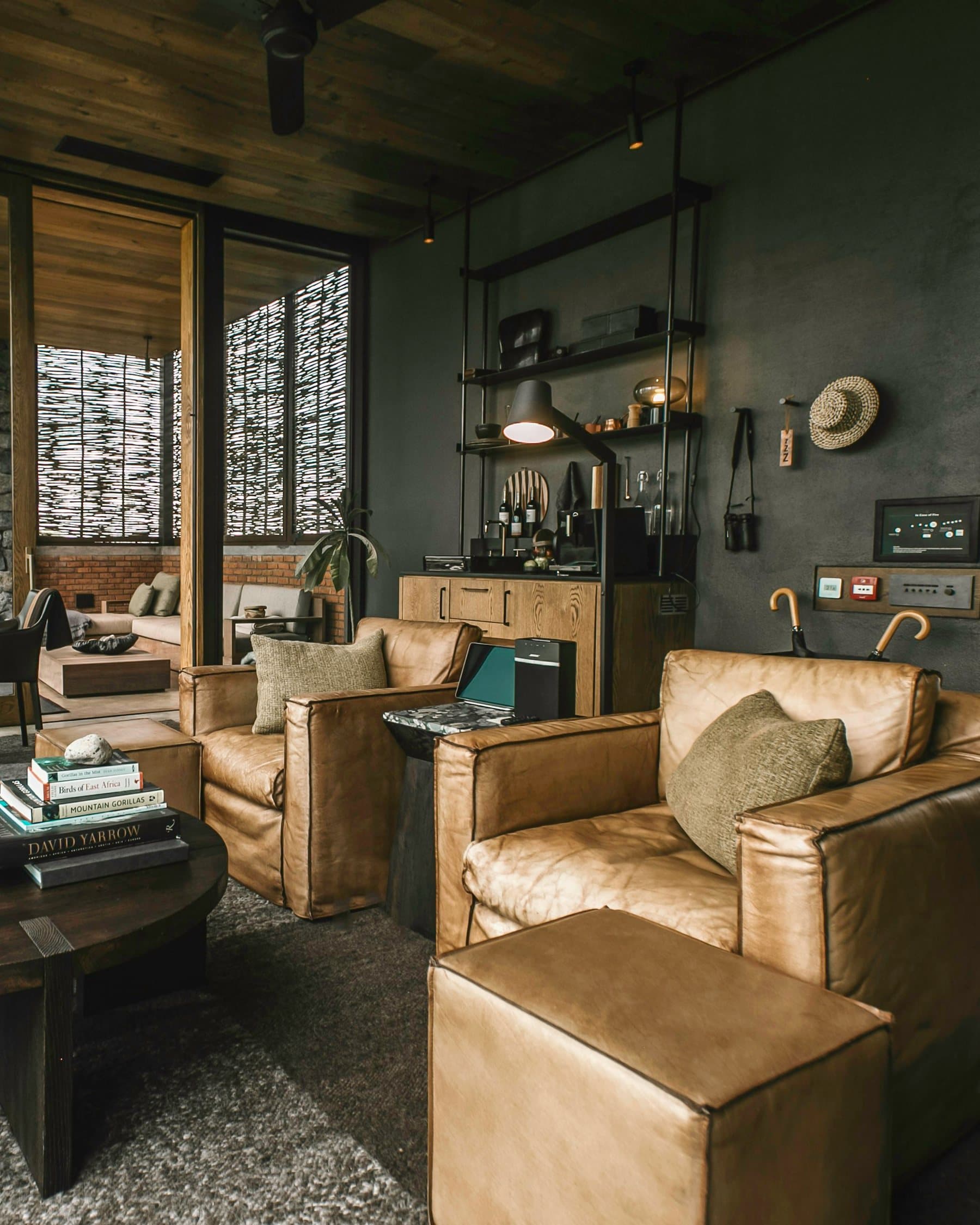 Worn leather armchairs, a round dark-wood table stacked with books and soft lamplight in a quiet members' lounge